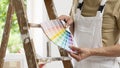 Hands of house painter man decorator choose the color using the sample swatch, work of the house to renovate, a wooden ladder and Royalty Free Stock Photo