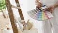 Hands of house painter man decorator choose the color using the sample swatch, work of the house to renovate, a wooden ladder with Royalty Free Stock Photo