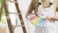 Hands of house painter man decorator choose the color using the sample swatch, work of the house to renovate, a wooden ladder and Royalty Free Stock Photo