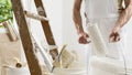 Hands of house painter man decorator work of home to renovate, using roller paint and holding white bucket, a wooden ladder with Royalty Free Stock Photo
