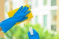 Hands of housekeeper cleaning mirror with yellow cloth.