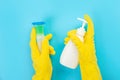 The hands of a housewife in yellow rubber protective gloves hold a bottle of household chemicals and a rag. Detergent for various