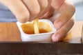 Hands of a hungry boy dipping in sauce and eating a fried potatoes on the summer terrace of the city fast food restaurant, close Royalty Free Stock Photo