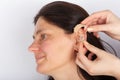 ^}Hands insertin hearing aid in womans ear Royalty Free Stock Photo