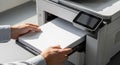 Hands inserting blank paper into a modern printer, showcasing the printing process in a bright office environment with emphasis on Royalty Free Stock Photo