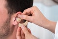 Hands inserting a hearing aid into a man's ear Royalty Free Stock Photo