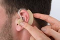 Hands inserting a hearing aid into a man's ear Royalty Free Stock Photo