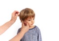 Hands inserting hearing aid in a preschooler ear. Studio shot, isolated on white background