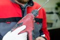 In the hands of the installer worker perforator red with traces of scratches and scuffs