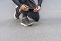 Hands of jogger young man tying shoelace on the road while workout in park. Healthy exercise comfortable sport shoes concept Royalty Free Stock Photo