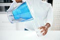 Hands, jug and glass of filter water to refresh with pure liquid hydration at home. Closeup, thirsty person and pouring