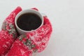 Hands keep a cup of coffee against the background of snow