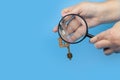 Hands with keys and a magnifying glass. Blue background Royalty Free Stock Photo