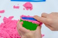 Hands of a kid playing with pink magic sand Royalty Free Stock Photo