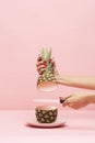 Hands with knife cutting an empty Pineapple on a pink background