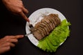 Hands with knife and fork sliced pork meat with lettuce leaves on a plate Royalty Free Stock Photo