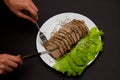 Hands with knife and fork sliced pork meat with lettuce leaves on a plate Royalty Free Stock Photo