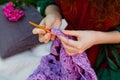 Hands are knitting a lilac shawl. Close-up of openwork crochet. Selective focus Royalty Free Stock Photo