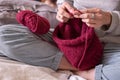 Hands knitting red coloured sweeter with needles close up