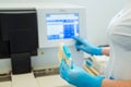 Hands of laboratory assistant loading sample tubes for coagulation test analysis and inputing data to coagulation