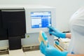 Hands of laboratory assistant loading sample tubes for coagulation test analysis and inputing data to coagulation