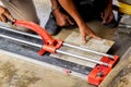 Hands of laborer using cutting tile machine at construction site