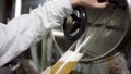 Hands of a labouring man in a white robe holding a test-tube while filling it with ale. A side view slow motion close up