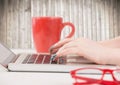 Hands with laptop and red coffee cup against blurry wood panel Royalty Free Stock Photo