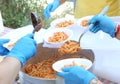 hands with latex gloves during meal distribution of pasta with t Royalty Free Stock Photo