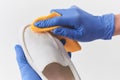 Hands in latex gloves washing a white leather slip-on shoe