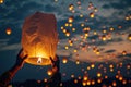 hands launching a Chinese paper traditional lantern into the evening sky