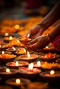 Hands lighting Diwali diyas, symbolizing the victory of light over darkness