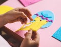 The hands of a little caucasian girl peel off a yellow felt sticker for a blue egg with her fingers Royalty Free Stock Photo