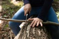 Hands of little girl or boy using a Swiss knife, sawing a piece of wood in the forest, nobody Royalty Free Stock Photo