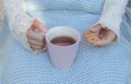 Hands of little girl in cozy hand warmers fingerless gloves holding cup of tea and cookie Royalty Free Stock Photo