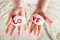 Hands of little girl hold two white smooth stones with syllables lo and ve painted red on white cloth background. Love Royalty Free Stock Photo