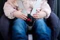 Hands of a little girl lie on the seat belt buckle of a child seat Royalty Free Stock Photo