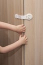 Hands of a little kid pulling the closet door closed with a special lock for child safety