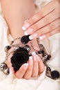 Hands with long artificial french manicured nails holding a necklace and black rose flower Royalty Free Stock Photo