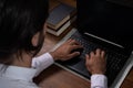 Hands of Long Haired Brown Hispanic Man Dressed in Shirt Typing on a Black Laptop on a Wooden Table Royalty Free Stock Photo