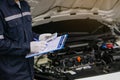 Hands of machinic man holding money, dollar banknotes and writing to the clipboard the checklist for repair machine, car service