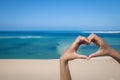 Hands making a heart sign at the beach