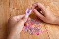 Hands making rubber band bracelet on the wooden table