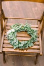 Hands making wedding wreath from eucalypthus and flowers hanging on wooden chair. Wedding, rustic eco decor.