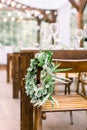 Hands making wedding wreath from eucalypthus and flowers hanging on wooden chair. Wedding, rustic eco decor. Tables