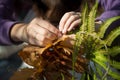 Hands making wreath of maple leaves and fern, close up