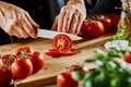 Hands of a male chef slicing a ripe tomato
