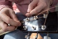 Hands male inserts new strings in an acoustic guitar. Repair of musical instruments. Royalty Free Stock Photo