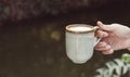 Hands of a man or barista holding cup of hot coffee latte with heart shaped foam art Royalty Free Stock Photo