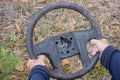 hands of a man in blue clothes holding an old black round dirty car steering wheel Royalty Free Stock Photo